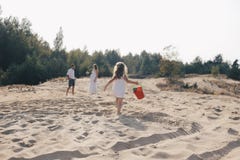 Mały caucasian dziewczyna bieg wzdłuż plaży w biel sukni z czerwonym wiadrem widok z powrotem obraz royalty free Mały caucasian dziewczyna bieg wzdłuż plaży w biel sukni z czerwonym wiadrem widok z powrotem obraz royalty free