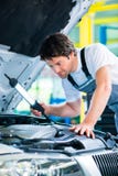 Meccanico che lavora nell'officina di servizio dell'automobile immagine stock libera da diritti Meccanico che lavora nell'officina di servizio dell'automobile immagine stock libera da diritti