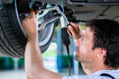 Mechanic working in car workshop on wheel Royalty Free Stock Photo Mechanic working in car workshop on wheel Royalty Free Stock Photo