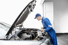 Mecánico europeo que examina un coche con la tableta Foto de archivo libre de regalías Mecánico europeo que examina un coche con la tableta Foto de archivo libre de regalías