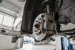 Mecânico de carro que inspeciona a roda de carro e o detalhe da suspensão do reparo Automóvel levantado na estação do serviço de imagens de stock Mecânico de carro que inspeciona a roda de carro e o detalhe da suspensão do reparo Automóvel levantado na estação do serviço de imagens de stock