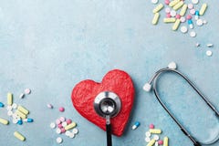 Medical stethoscope, red heart and drug pills on blue background top view. Healthy and blood pressure concept. Stock Photo Medical stethoscope, red heart and drug pills on blue background top view. Healthy and blood pressure concept. Stock Photo