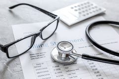 Medical treatmant billing statement with stethoscope and glasses on stone background stock photo Medical treatmant billing statement with stethoscope and glasses on stone background stock photo