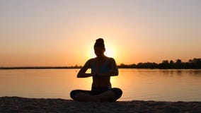 Meditation nahe dem Meer und Handelnyoga auf einem Strand bei Sonnenuntergang Meditation nahe dem Meer und Handelnyoga auf einem Strand bei Sonnenuntergang