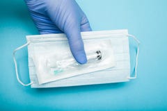 Medizinische Maske und eine Spritze in der Hand des Doktors lizenzfreie stockbilder Medizinische Maske und eine Spritze in der Hand des Doktors lizenzfreie stockbilder