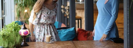 meeting two women in a cafe for coffee. one stood up to greet the second. blue dress, dress in flower, on the carved table is a cu royalty free stock photography meeting two women in a cafe for coffee. one stood up to greet the second. blue dress, dress in flower, on the carved table is a cu royalty free stock photography