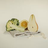 Meias metades da pera, do limão e dos brócolis em um saco eco-amigável imagens de stock Meias metades da pera, do limão e dos brócolis em um saco eco-amigável imagens de stock