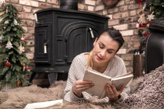 Meisje die een boek in een comfortabele huisatmosfeer lezen dichtbij de open haard royalty-vrije stock fotografie Meisje die een boek in een comfortabele huisatmosfeer lezen dichtbij de open haard royalty-vrije stock fotografie