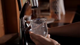 Meisje die een glas water van de kraan in de gootsteen en het drinken krijgen Meisje die een glas water van de kraan in de gootsteen en het drinken krijgen