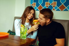 Meisje die haar vriend een hamburger voeden stock afbeeldingen Meisje die haar vriend een hamburger voeden stock afbeeldingen
