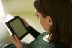 Meisje die literatuur met eBook thuis bestuderen stock afbeelding Meisje die literatuur met eBook thuis bestuderen stock afbeelding