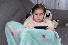Meisje die met hoofdtelefoons in de telefoon spelen royalty-vrije stock fotografie Meisje die met hoofdtelefoons in de telefoon spelen royalty-vrije stock fotografie