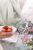 Meisje die verse aardbeien in een plaat houden Op de bank in de comfortabele woonkamer Toebehoren voor hobby het breien De ochten royalty-vrije stock foto's Meisje die verse aardbeien in een plaat houden Op de bank in de comfortabele woonkamer Toebehoren voor hobby het breien De ochten royalty-vrije stock foto's