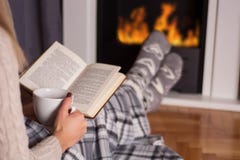 Meisje voor het boek van de open haardlezing en verwarmende voeten op brand stock afbeeldingen Meisje voor het boek van de open haardlezing en verwarmende voeten op brand stock afbeeldingen