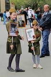 Meisjes in militaire eenvormige greepportretten van hun verwanten in het actie` Onsterfelijke regiment ` op Overwinningsdag in Vo royalty-vrije stock foto Meisjes in militaire eenvormige greepportretten van hun verwanten in het actie` Onsterfelijke regiment ` op Overwinningsdag in Vo royalty-vrije stock foto