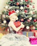 Meisjezitting dichtbij Kerstboom met een grote gift Stock Foto Meisjezitting dichtbij Kerstboom met een grote gift Stock Foto