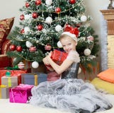 Meisjezitting dichtbij Kerstboom met een grote gift Royalty-vrije Stock Afbeelding Meisjezitting dichtbij Kerstboom met een grote gift Royalty-vrije Stock Afbeelding