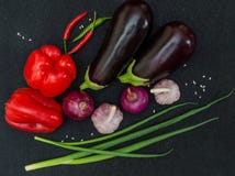 Melanzane fresche, pepe, aglio, cipolla su fondo nero fotografia stock Melanzane fresche, pepe, aglio, cipolla su fondo nero fotografia stock
