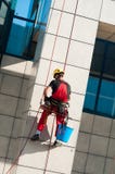 Man cleaning office building hanging on ropes