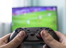 Men`s hands with a joystick on the background of a TV, playing football, close-up stock images Men`s hands with a joystick on the background of a TV, playing football, close-up stock images
