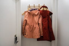 Men and women winter jacket hang at wall hook at house door stock photography Men and women winter jacket hang at wall hook at house door stock photography