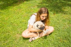 Menina adolescente bonita que olha um v?deo engra?ado em um smartphone com seu c?o em um parque do ver?o foto de stock royalty free Menina adolescente bonita que olha um v?deo engra?ado em um smartphone com seu c?o em um parque do ver?o foto de stock royalty free