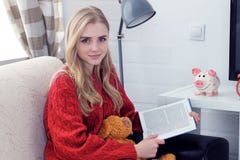 Menina adolescente caucasiano feliz que descansa no sofá na sala de visitas quando livro de leitura Foto de Stock Menina adolescente caucasiano feliz que descansa no sofá na sala de visitas quando livro de leitura Foto de Stock