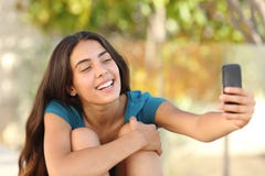 Menina adolescente feliz que toma um retrato do selfie com seu telefone esperto imagens de stock royalty free Menina adolescente feliz que toma um retrato do selfie com seu telefone esperto imagens de stock royalty free
