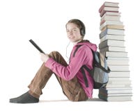 A menina adolescente lê o ebook perto da pilha de livros Foto de Stock Royalty Free A menina adolescente lê o ebook perto da pilha de livros Foto de Stock Royalty Free