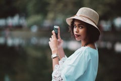 A menina afro-americano está fotografando a água do lago da noite através de imagem de stock A menina afro-americano está fotografando a água do lago da noite através de imagem de stock