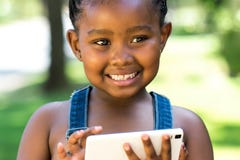 Menina afro bonito que joga no telefone esperto fotografia de stock royalty free Menina afro bonito que joga no telefone esperto fotografia de stock royalty free