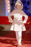 A menina anda pista de decolagem durante o desfile de moda dos miúdos imagem de stock A menina anda pista de decolagem durante o desfile de moda dos miúdos imagem de stock