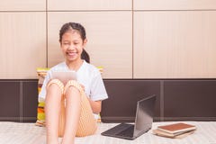 Menina asiática de sorriso feliz que usa o tablet pc para estudar em seu b imagens de stock Menina asiática de sorriso feliz que usa o tablet pc para estudar em seu b imagens de stock