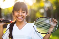 Menina asiática pequena que guarda uma raquete de badminton imagem de stock royalty free Menina asiática pequena que guarda uma raquete de badminton imagem de stock royalty free
