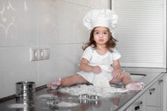 A menina bonita aprende cozinhar uma refeição na cozinha fotos de stock A menina bonita aprende cozinhar uma refeição na cozinha fotos de stock