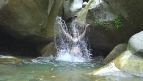 A menina bonita do movimento lento espirra na água pelas mãos no rio da montanha na floresta tropical verde com a cachoeira peque vídeos de arquivo A menina bonita do movimento lento espirra na água pelas mãos no rio da montanha na floresta tropical verde com a cachoeira peque vídeos de arquivo
