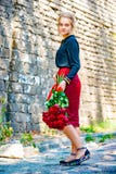 A menina bonita e 'sexy' com um ramalhete de rosas vermelhas está no fundo de uma parede de tijolo velha imagem de stock A menina bonita e 'sexy' com um ramalhete de rosas vermelhas está no fundo de uma parede de tijolo velha imagem de stock