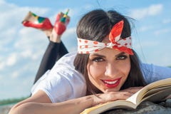Menina bonita que encontra-se na parede e que aprecia uma leitura do livro fotos de stock royalty free Menina bonita que encontra-se na parede e que aprecia uma leitura do livro fotos de stock royalty free