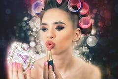 A menina bonita que faz a composição, usando o batom, faz o penteado Forma imagem de stock A menina bonita que faz a composição, usando o batom, faz o penteado Forma imagem de stock