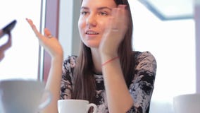 Menina bonita que mostra uma amiga do smartphone no café vídeos de arquivo Menina bonita que mostra uma amiga do smartphone no café vídeos de arquivo