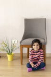 Menina bonito ao lado de uma cadeira em casa imagem de stock Menina bonito ao lado de uma cadeira em casa imagem de stock