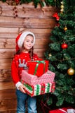 Menina bonito da criança pequena com as caixas de presente atuais perto da árvore em casa foto de stock Menina bonito da criança pequena com as caixas de presente atuais perto da árvore em casa foto de stock