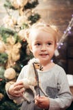A menina bonito da criança pequena está decorando a árvore de Natal dentro Presentes da abertura no Natal e no ano novo Pequeno b imagem de stock royalty free A menina bonito da criança pequena está decorando a árvore de Natal dentro Presentes da abertura no Natal e no ano novo Pequeno b imagem de stock royalty free