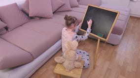 Menina com o brinquedo do coelho perto do quadro-negro video estoque Menina com o brinquedo do coelho perto do quadro-negro video estoque