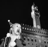 Menina de sorriso na frente de Palazzo Vecchio que come o bastão do Natal imagens de stock royalty free Menina de sorriso na frente de Palazzo Vecchio que come o bastão do Natal imagens de stock royalty free