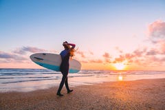 A menina desportiva da ressaca vai a surfar Mulher com prancha e por do sol ou nascer do sol no oceano imagens de stock royalty free A menina desportiva da ressaca vai a surfar Mulher com prancha e por do sol ou nascer do sol no oceano imagens de stock royalty free