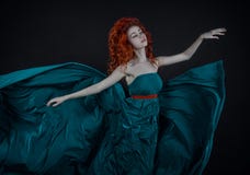 Menina em um vestido de seda, uma dança ruivo bonita da menina em um voo do vestido do verde longo no ar, um vestido do verde lon foto de stock royalty free Menina em um vestido de seda, uma dança ruivo bonita da menina em um voo do vestido do verde longo no ar, um vestido do verde lon foto de stock royalty free