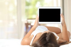 Menina em uma cama que mostra uma tela vazia da tabuleta fotografia de stock royalty free Menina em uma cama que mostra uma tela vazia da tabuleta fotografia de stock royalty free