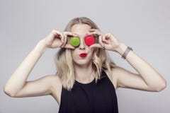 Menina engraçada que faz as caras com os dois bolinhos de amêndoa colocados em vez dos olhos A menina tem o cabelo louro encaraco imagem de stock royalty free Menina engraçada que faz as caras com os dois bolinhos de amêndoa colocados em vez dos olhos A menina tem o cabelo louro encaraco imagem de stock royalty free
