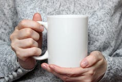 A menina está guardando o copo branco nas mãos Caneca branca nas mãos da mulher Foto de Stock A menina está guardando o copo branco nas mãos Caneca branca nas mãos da mulher Foto de Stock